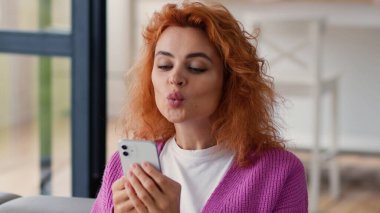 Mutlu gülümseyen beyaz kadın kullanıcı aygıtı bağımlısı, cep telefonu kullanan, cep telefonu ekranlı akıllı telefon kullanan, sosyal medya buluşması uygulaması internetten sohbet eden ev kanepedeki erkek arkadaş.