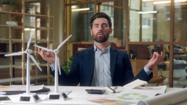 Mühendis meditasyoncu rüzgar türbini projesi modelleri yeşil rahatlama yenilenebilir enerji tasarımı odaklı beyaz erkek barışçı iş adamı farkındalık ofiste sürdürülebilir yenilik