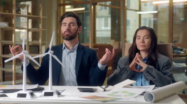 Rüzgâr türbini meditasyon yapan çok ırklı iş adamları. Yel değirmeni modelleri. Koreli kadın Kafkasyalı.