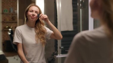 Güzel, genç bir bayan, aynaya bakan, yüz masajı yapan, gua sha masajı yapan, beyaz tenli, beyaz, güzel, masaj aleti, güzellik kremi kullanan, spa terapisi uygulayan bir kız.