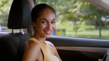 Başarılı, mutlu, Afro-Amerikalı bir kadın, kameraman kız arabasının içindeki gülümsemeye bakıyor. Yeni bir otomobil nakliyecisi, iş kadını, gülen bir araç, kiralık bir araç satın alıyor.