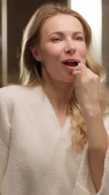 Diş fırçası tutan, beyaz dişlerini fırçalayan, beyaz dişlerini fırçalayan mutlu bir kadın. Kafkasyalı, gülümseyen bir kadın.