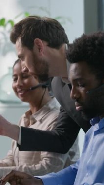 Çok ırklı bir çağrı merkezi, gülümseyen Kafkasyalı patron, Hintli kadın gözlemciyi işaret ederek, ofis çalışanlarını, iş merkezini, müşteri hizmetlerini, Afrikalı erkek kulaklığı yardım hattı eğitimini açıklıyor.