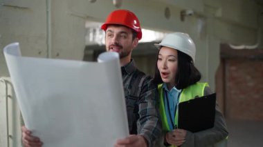 Çok uluslu mutlu mühendisler inşaat sahası teftiş planı başarı güvenlik ilerleme planlama çeşitli işçiler Asyalı kadın Kafkasyalı erkek proje analizi