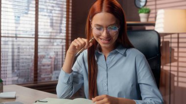 Kafkasyalı iş kadını veri bilgi şemasını analiz ediyor dizüstü bilgisayara benzeyen notlar yazıyor iyi bir işi var gibi görünüyor masa başında evraklarla çalışan mutlu bir iş kadını gülümsüyor.