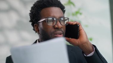 Kızgın, kızgın, Afrikalı, Amerikalı iş adamı bağırıyor. Ofiste konuşan cep telefonu belgelerini tartışıyor. Etnik işadamı, öfkeli, tartışmalı, çatışmalı, akıllı telefon görüşmesi yapıyor.