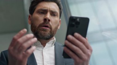 Mutsuz Kafkasyalı orta yaşlı iş adamının cep telefonuyla kötü haberler okuması ofiste hayal kırıklığı yaratıyor. Stresli iş adamı yöneticisi, akıllı telefon sorunu.