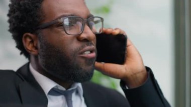 Sinirli, sinirli, Afro-Amerikan iş adamının cep telefonuyla konuşması, bağırması, bağırması, tartışması ofis camına bakması, kızgın iş adamı stres iletişimi.