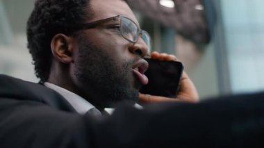 Kapatın sinirli duygusal stresli Afrikalı Amerikalı iş adamı bağırarak ofisteki etnik sinirli iş adamının cep telefonuyla yaptığı tartışmayı tartışıyordu.