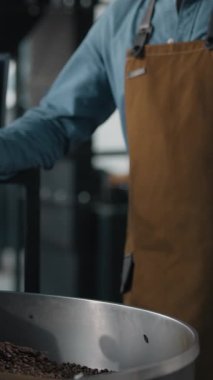 Kafkasyalı işçi kahve kızartılmış kumaş endüstrisinde çalışıyor. Kavurma makinesinin yanında kakao çekirdekleri karıştırıyor. Konuşan cep telefonu arıyor.