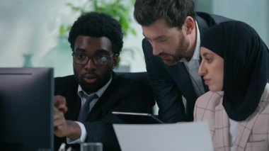 Bilgisayarlı ve kağıtlı üç çok ırklı iş arkadaşı, çok ırklı ekran çeşitliliğine sahip yönetici iş arkadaşlarını inceleyerek birlikte çalışma konusunu görüştüler.