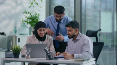 Üç Arap meslektaşı Müslüman iş arkadaşları Hindu iş ortakları, yöneticiler, iş adamları birlikte çalışanlar, iş yerinde kameraya bakıp gülümseyerek konuşmalar.