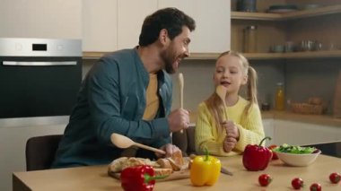 Kafkas ailesi bekar baba baba baba baba birlikte yemek pişiriyor baba çocuk kız çocuk kız çocuk kaşık içinde şarkı söylüyor mikrofon gibi şarkı söylüyor mutfakta eğleniyor baba gülüyor