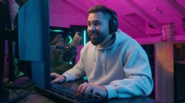 Gülümseyen Kafkasyalı erkek oyuncu erkek oyuncu. Gece online oyun oynayan erkek oyuncu sinirlenmiş, sinirli, sinirli ve başarısız sonuç bağımlılığı neon oda oyuncularının yumruklarını masaya vuruyor.