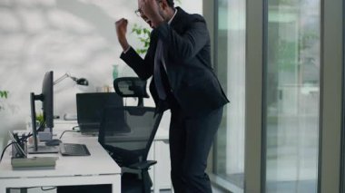 Ofiste mutlu bir iş adamı, Afrikalı Amerikalı işadamı, erkek işadamı, işveren, bilgisayar yazan, zafer kazanan, atlayan, başarılı bir iş adamı.