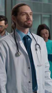 Kendinden emin, mutlu, beyaz erkek, erkek, tıp öğrencisi, doktor, çocuk doktoru, steteskop uzmanı kameraların el ele tutuşması, hastane kliniğinde çapraz bağlama.