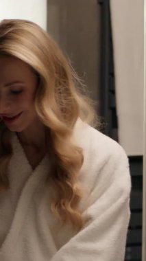 Sağlıklı, beyaz kadın derisi bornozlu kadın modeline makyaj malzemesi siliyor yüzünü pamukla siliyor ev banyosunda kozmetik yumuşak cilt nemini çıkarıyor.