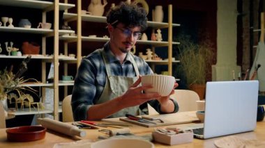 Potter 'lı adam el yapımı kase yontuyor erkek heykeltıraş heykeltıraş tasarımcı Kafkasyalı adam gülümsüyor tabak satıyor seramik satıyor küçük işletme sahibi el yapımı çömlek atölyesi gösteriyor