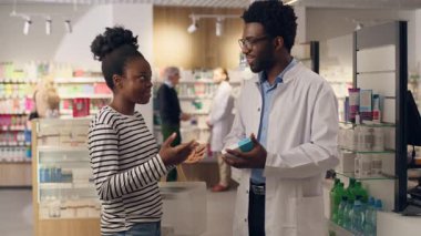 Eczacı, eczacı tavsiyesine yardımcı olur. Eczane sağlık hizmetleri danışmanlığında vitamin satın alır. Afro-Amerikan erkek kadın tavsiyesi.