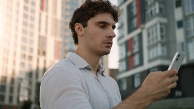 Kafkasyalı bir adam cep telefonu kullanıyor, akıllı telefon kullanıyor, sosyal medyada sohbet ediyor, internet üzerinden sohbet ediyor, gülümsüyor, uygulama yapıyor, erkek öğrenci aletleri, iş dünyası işadamı sokakta yürüyor, şehir dışına çıkıyor.