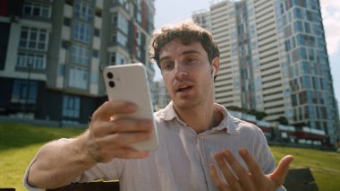 Kafkasyalı adam cep telefonu akıllı telefonu kullanıyor online toplantı kulaklık sallıyor erkek iş adamı blogcu iletişimi videolu görüşme iş ortaklığı açık hava vlogger