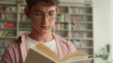 Kafkasyalı genç adam kitap okurken ağzı açık düşüncelere dalmış üniversite kütüphanesinde sınavlara hazırlanmayı düşünmüş genç çocuk edebiyat eğitimi okumuş ev ödevi okumuş düşünceli davranmış.