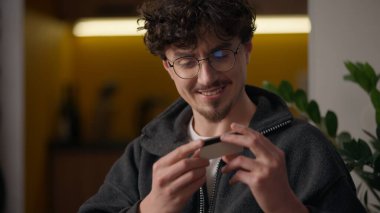 Kafkasyalı mutlu hipster alıcısı elinde kredi kartı ile internetsiz ödeme kredisi tutuyor memnun müşterisi evdeki adamın veri dizüstü bilgisayarına girip ürün web sitesi uygulaması satın alıyor banka tüketiciliği