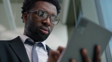 Mutlu Afrikalı Amerikalı işadamı dijital tablet modern teknoloji kullanarak gülümsüyor başarılı profesyonel erkek yönetici şirket girişimcisi internet üzerinde çalışıyor.