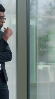 Sorunu çözmeyi düşünen Afro-Amerikalı işadamının ofis penceresine bakması sorunlu iş başarısızlığına karar vermesi yorgun iş adamı zor karar vermek cama yaslanmak erkeğin tereddüt ettiğini düşünüyor.