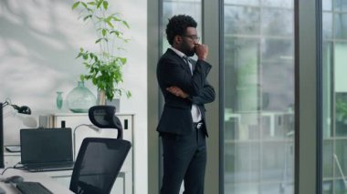 Dalgın Afrikalı Amerikalı iş adamı, kaygılarını dile getirdi. Pencereden bakıp çözüm arayışları kötü bir sorun yaratıyor. Etnik iş adamı çok çalışıyor.
