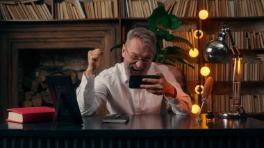 Kendinden emin, yaşlı, beyaz, olgun bir erkek kamera önünde el ele tutuşmuş ofis işadamı yakışıklı, yaşlı çalışan portresi liderinin içindeki iş adamına bakıyor.