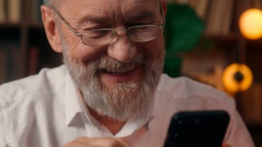 Kendinden emin, yaşlı, beyaz, olgun bir erkek kamera önünde el ele tutuşmuş ofis işadamı yakışıklı, yaşlı çalışan portresi liderinin içindeki iş adamına bakıyor.