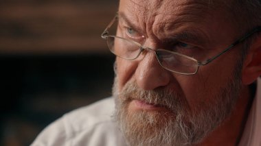 Kendinden emin, yaşlı, beyaz, olgun bir erkek kamera önünde el ele tutuşmuş ofis işadamı yakışıklı, yaşlı çalışan portresi liderinin içindeki iş adamına bakıyor.