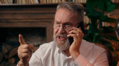 Kendinden emin, yaşlı, beyaz, olgun bir erkek kamera önünde el ele tutuşmuş ofis işadamı yakışıklı, yaşlı çalışan portresi liderinin içindeki iş adamına bakıyor.