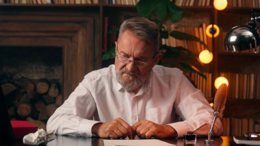 Kendinden emin, yaşlı, beyaz, olgun bir erkek kamera önünde el ele tutuşmuş ofis işadamı yakışıklı, yaşlı çalışan portresi liderinin içindeki iş adamına bakıyor.