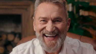 Kendinden emin, yaşlı, beyaz, olgun bir erkek kamera önünde el ele tutuşmuş ofis işadamı yakışıklı, yaşlı çalışan portresi liderinin içindeki iş adamına bakıyor.