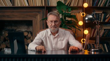 Kendinden emin, yaşlı, beyaz, olgun bir erkek kamera önünde el ele tutuşmuş ofis işadamı yakışıklı, yaşlı çalışan portresi liderinin içindeki iş adamına bakıyor.