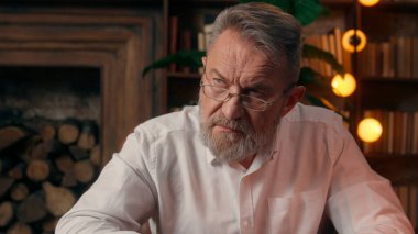 Kendinden emin, yaşlı, beyaz, olgun bir erkek kamera önünde el ele tutuşmuş ofis işadamı yakışıklı, yaşlı çalışan portresi liderinin içindeki iş adamına bakıyor.