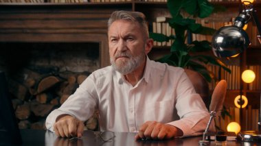 Kendinden emin, yaşlı, beyaz, olgun bir erkek kamera önünde el ele tutuşmuş ofis işadamı yakışıklı, yaşlı çalışan portresi liderinin içindeki iş adamına bakıyor.