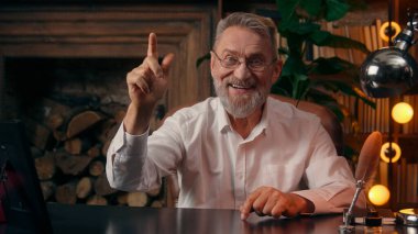 Kendinden emin, yaşlı, beyaz, olgun bir erkek kamera önünde el ele tutuşmuş ofis işadamı yakışıklı, yaşlı çalışan portresi liderinin içindeki iş adamına bakıyor.