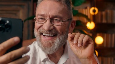 Kendinden emin, yaşlı, beyaz, olgun bir erkek kamera önünde el ele tutuşmuş ofis işadamı yakışıklı, yaşlı çalışan portresi liderinin içindeki iş adamına bakıyor.