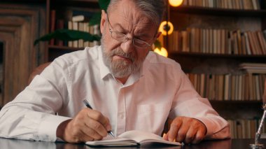 Kendinden emin, yaşlı, beyaz, olgun bir erkek kamera önünde el ele tutuşmuş ofis işadamı yakışıklı, yaşlı çalışan portresi liderinin içindeki iş adamına bakıyor.