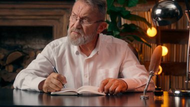 Kendinden emin, yaşlı, beyaz, olgun bir erkek kamera önünde el ele tutuşmuş ofis işadamı yakışıklı, yaşlı çalışan portresi liderinin içindeki iş adamına bakıyor.