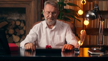 Kendinden emin, yaşlı, beyaz, olgun bir erkek kamera önünde el ele tutuşmuş ofis işadamı yakışıklı, yaşlı çalışan portresi liderinin içindeki iş adamına bakıyor.