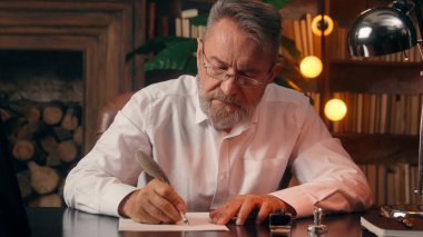 Kendinden emin, yaşlı, beyaz, olgun bir erkek kamera önünde el ele tutuşmuş ofis işadamı yakışıklı, yaşlı çalışan portresi liderinin içindeki iş adamına bakıyor.