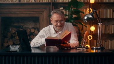 Kendinden emin, yaşlı, beyaz, olgun bir erkek kamera önünde el ele tutuşmuş ofis işadamı yakışıklı, yaşlı çalışan portresi liderinin içindeki iş adamına bakıyor.