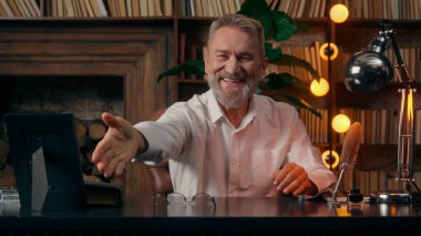 Kendinden emin, yaşlı, beyaz, olgun bir erkek kamera önünde el ele tutuşmuş ofis işadamı yakışıklı, yaşlı çalışan portresi liderinin içindeki iş adamına bakıyor.