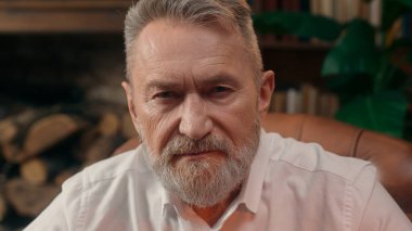 Kendinden emin, yaşlı, beyaz, olgun bir erkek kamera önünde el ele tutuşmuş ofis işadamı yakışıklı, yaşlı çalışan portresi liderinin içindeki iş adamına bakıyor.