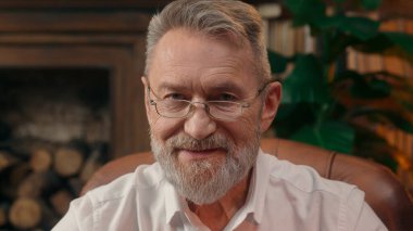 Kendinden emin, yaşlı, beyaz, olgun bir erkek kamera önünde el ele tutuşmuş ofis işadamı yakışıklı, yaşlı çalışan portresi liderinin içindeki iş adamına bakıyor.