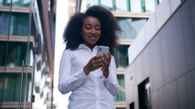 Afrika kökenli Amerikalı bir kadın cep telefonu kullanıyor. Akıllı telefon kullanıyor. İnternette mesajlaşmayı düşünüyor.